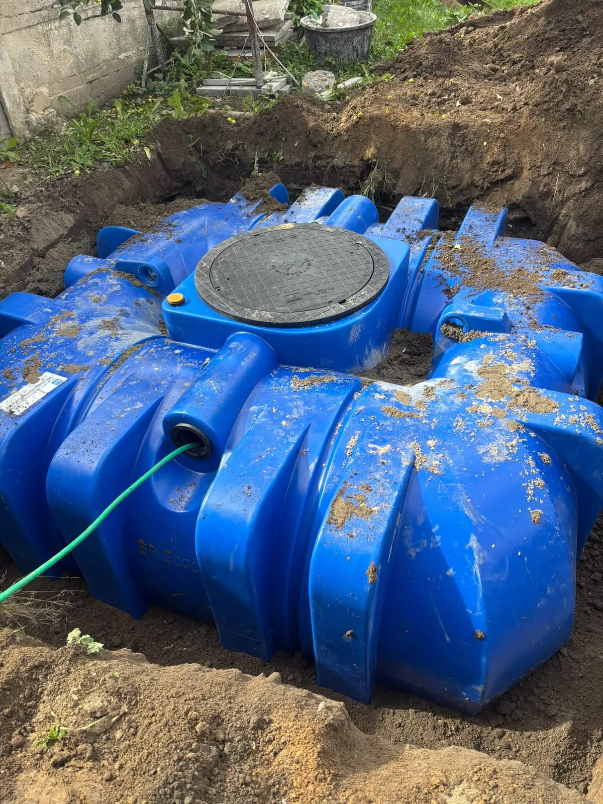 Blauwe kunststof regenput in de uitgegraven tuin in Drongen